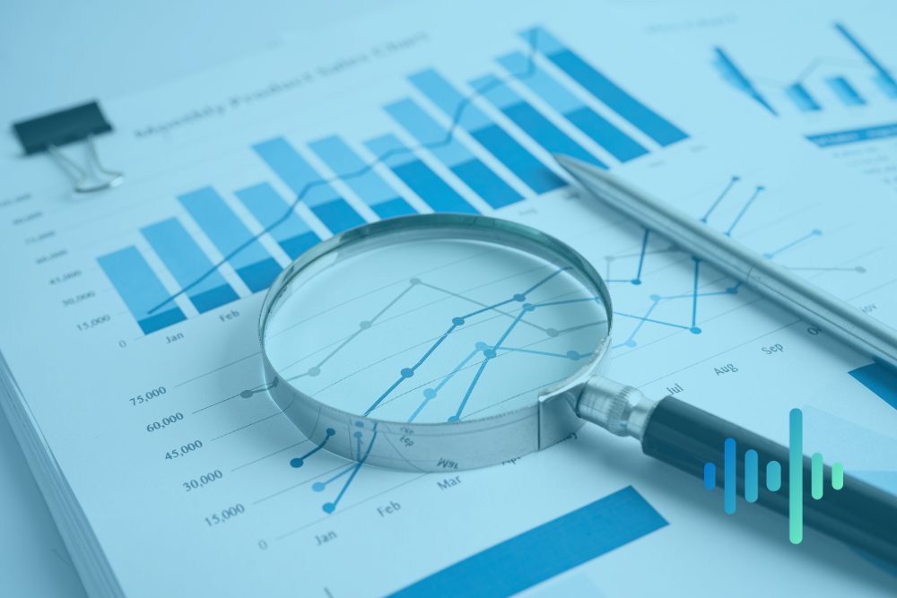 Magnifying glass and pen resting on printed bar charts and line graphs in a blue tint, with a waveform