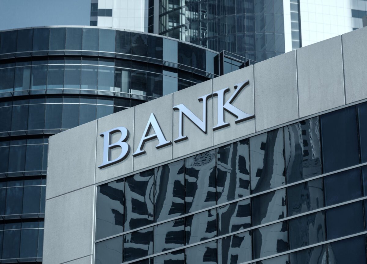 Modern glass office building with large BANK lettering on its stone corner facade