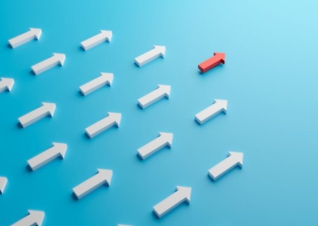 Rows of white arrows pointing the same way on a blue background, with a single red arrow breaking away in a different direction.