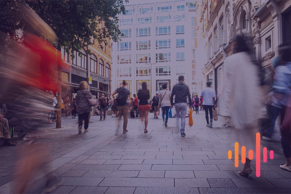 Shoppers walking along a busy city street in motion blur, with an orange and pink waveform
