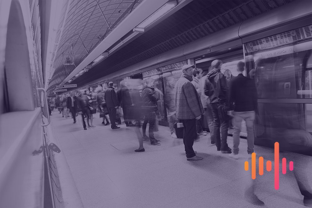 Commuters waiting on an underground platform as a train pulls in, in a muted purple tint