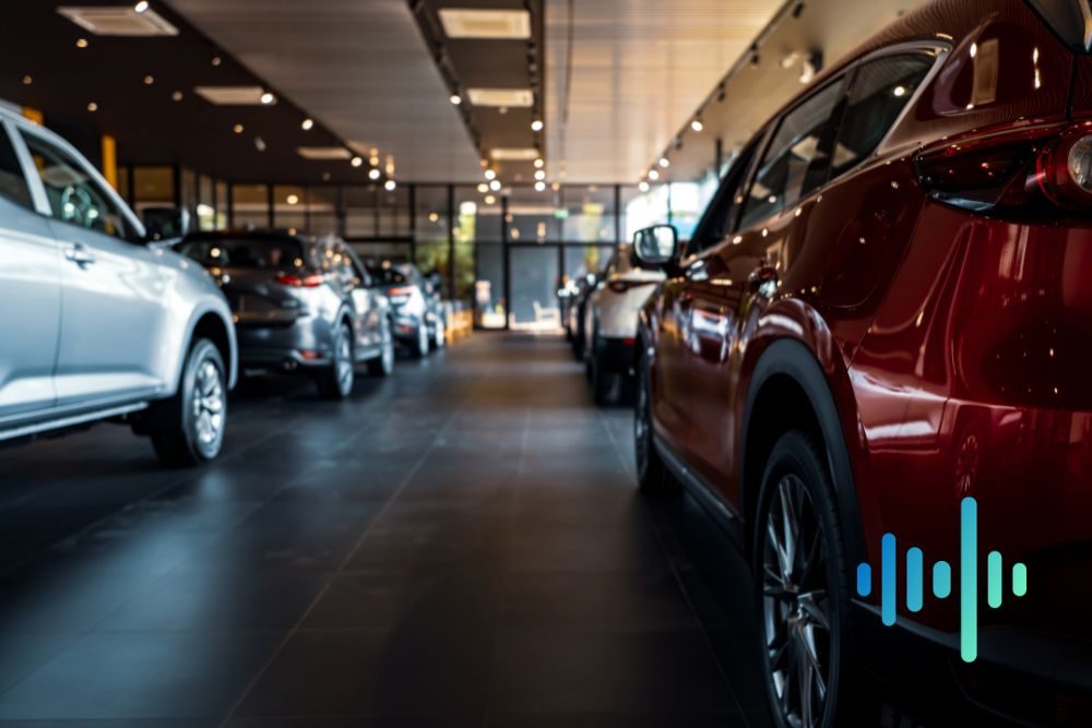 Row of new cars in a dim showroom aisle with a red car in the foreground, with a blue and teal waveform