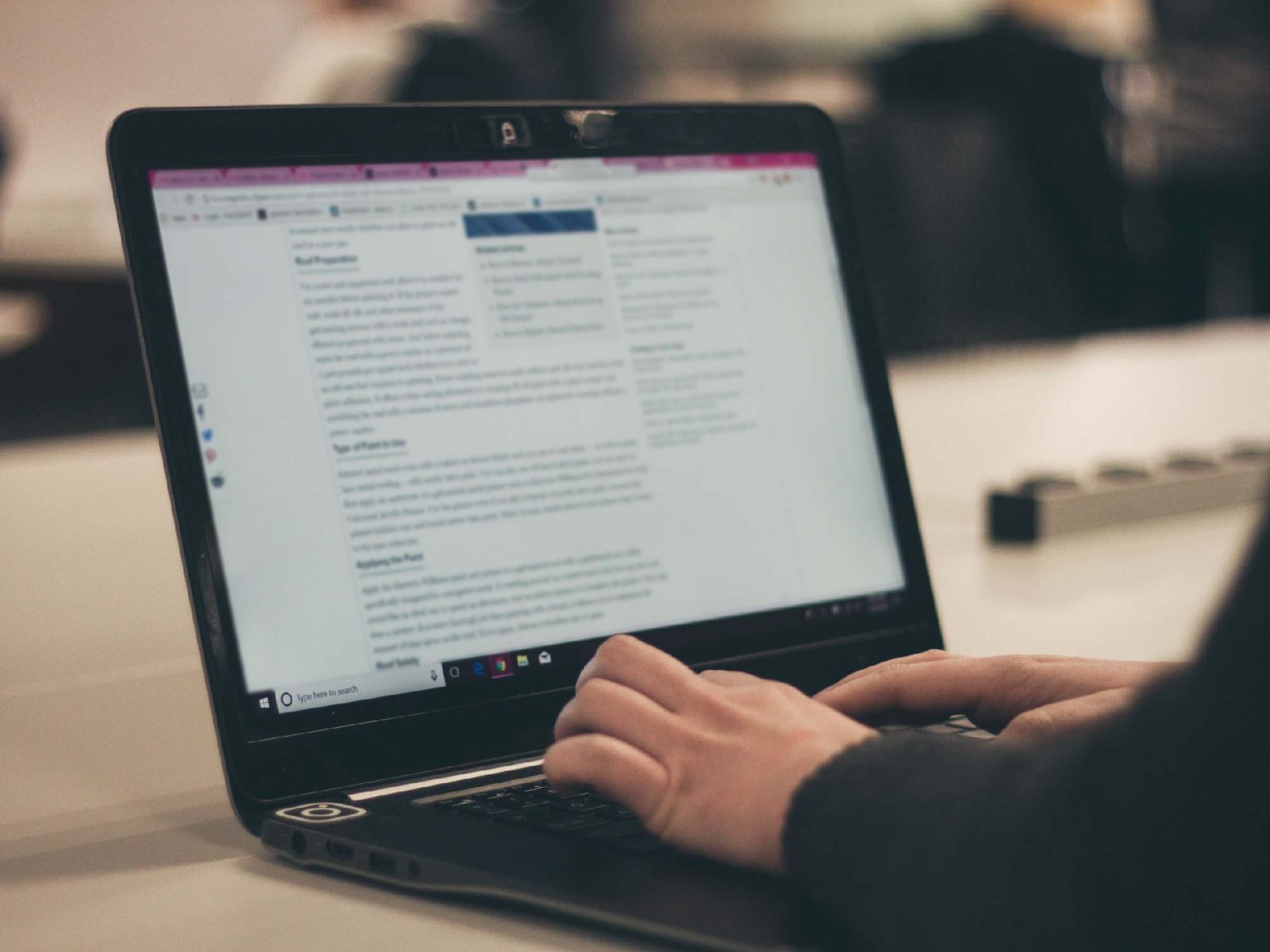 Close-up of hands typing on a laptop displaying a text document in a dim room
