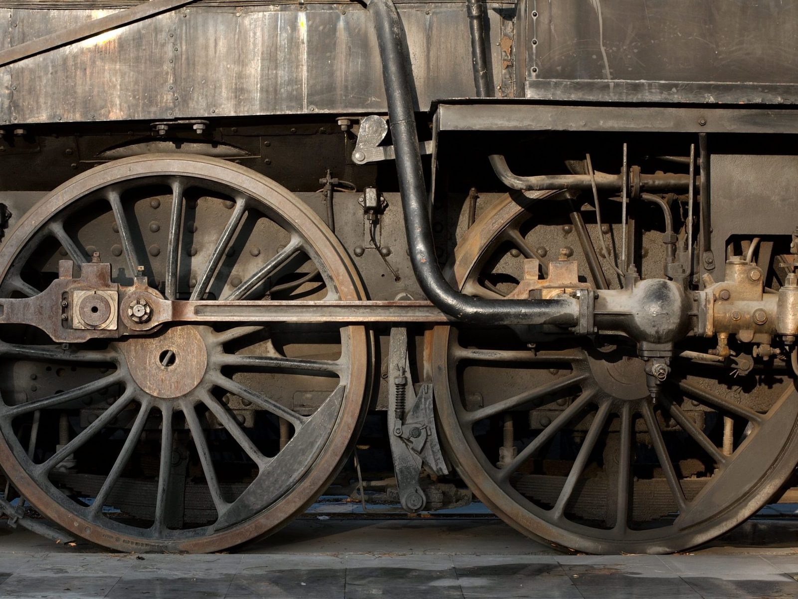Close-up of the large spoked driving wheels and connecting rods of an old steam locomotive
