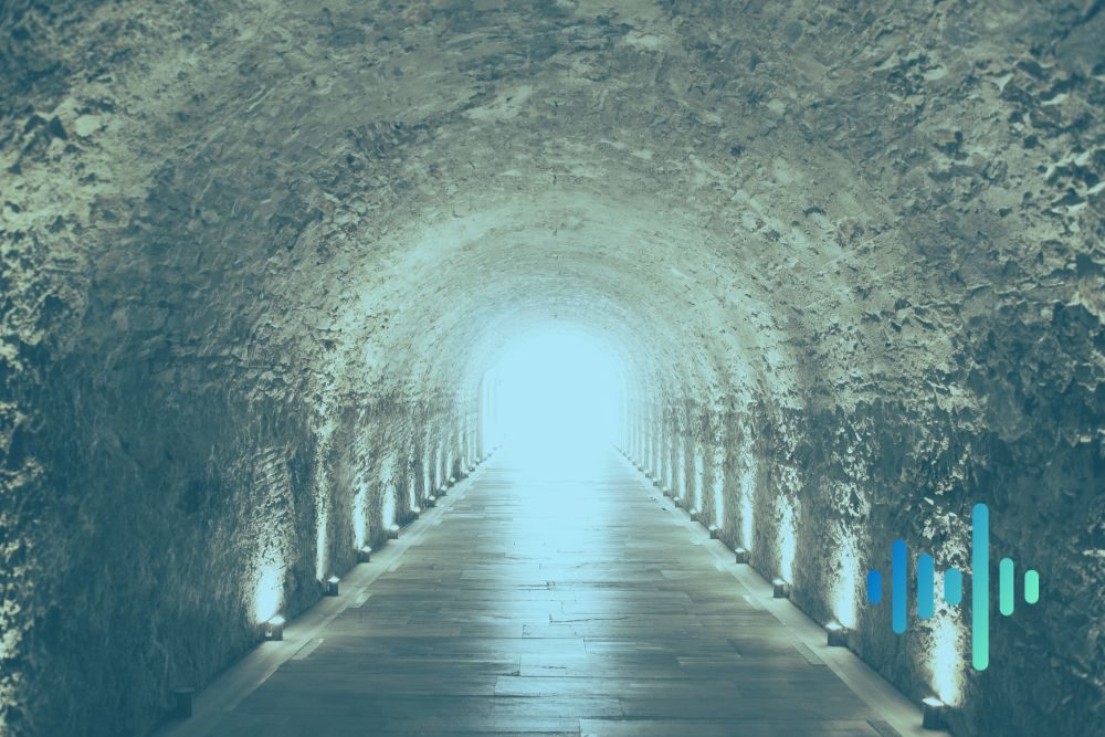 Stone tunnel lined with small lights leading towards a bright opening, in a blue-green tint with a waveform