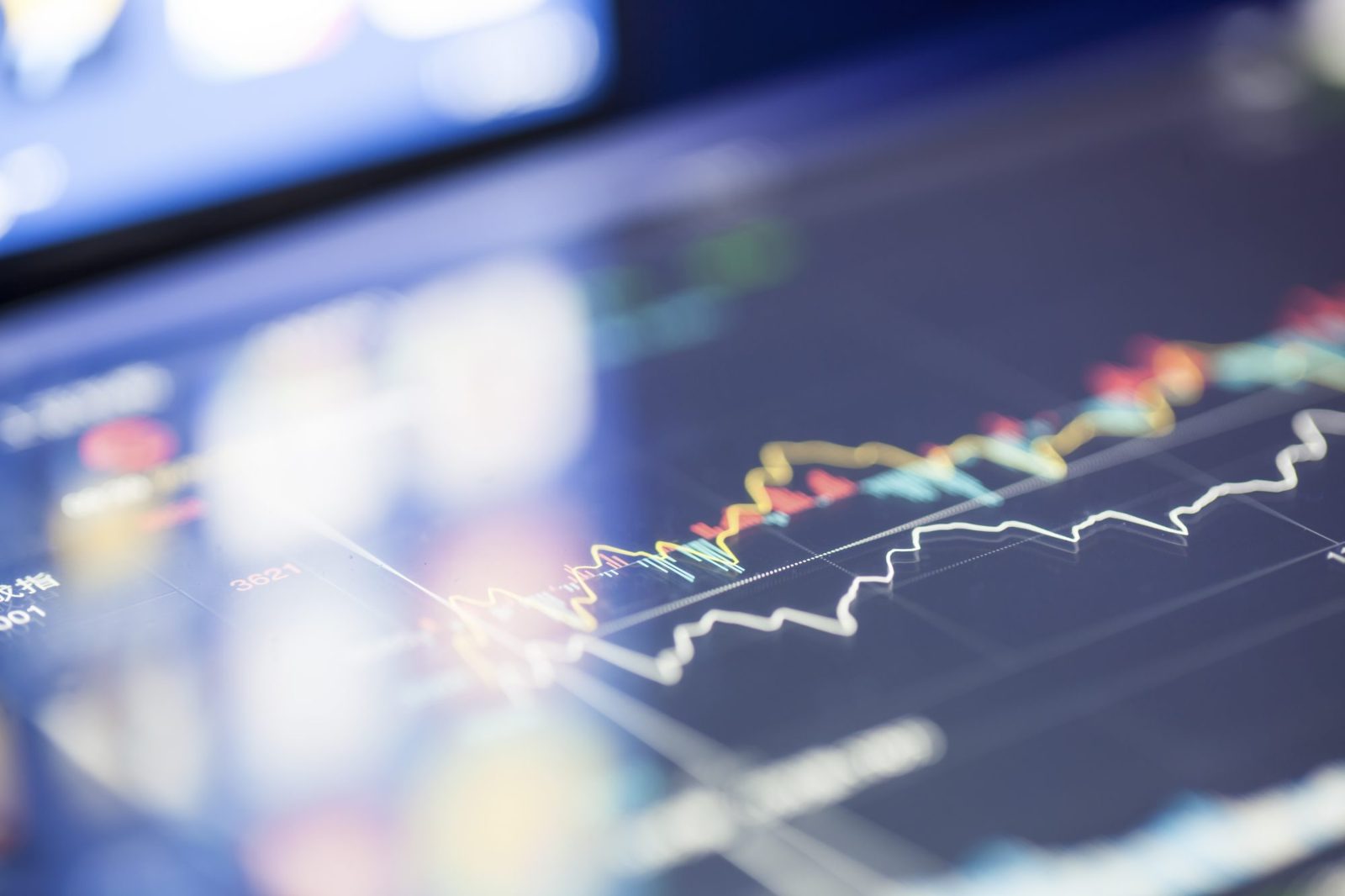 Close-up of a trading screen showing coloured price lines on a chart, softly out of focus