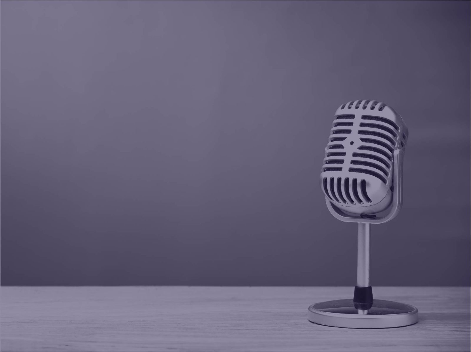 Vintage chrome microphone on a stand on a table, under a purple tint
