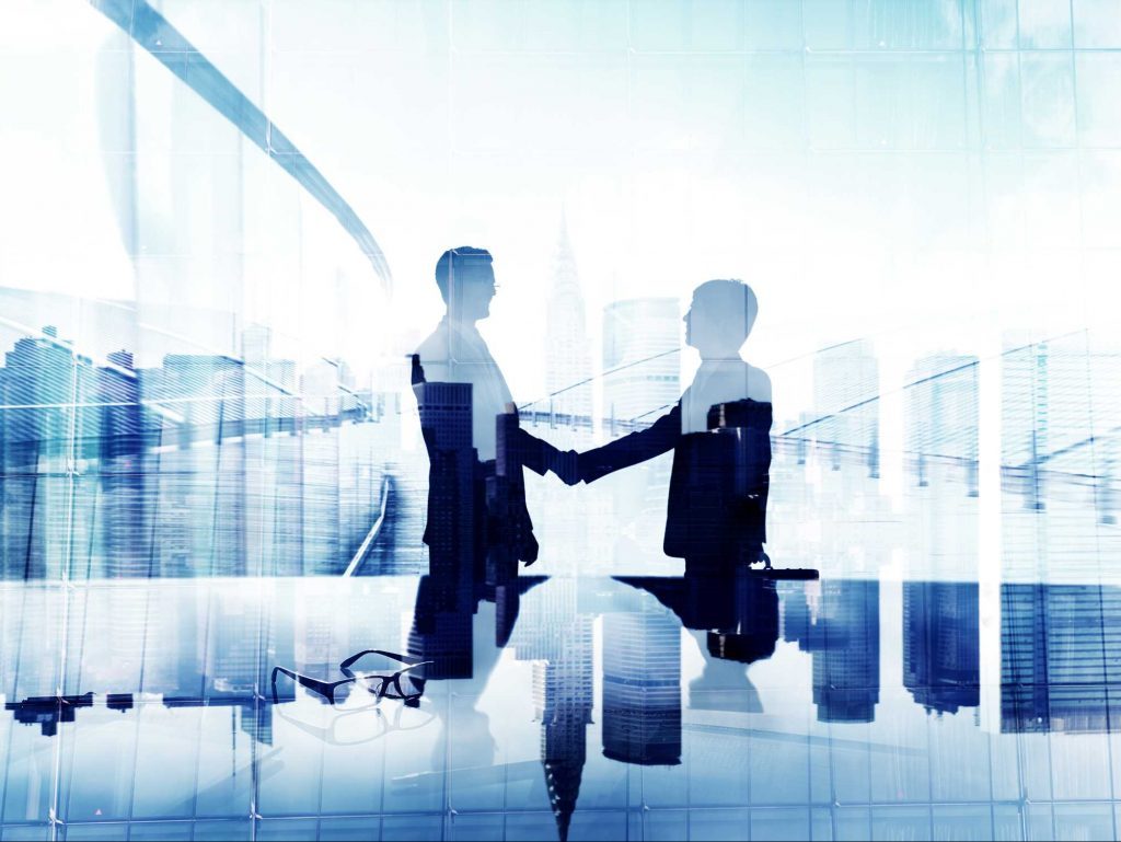 Silhouettes of two business people shaking hands, blended with a blue city skyline