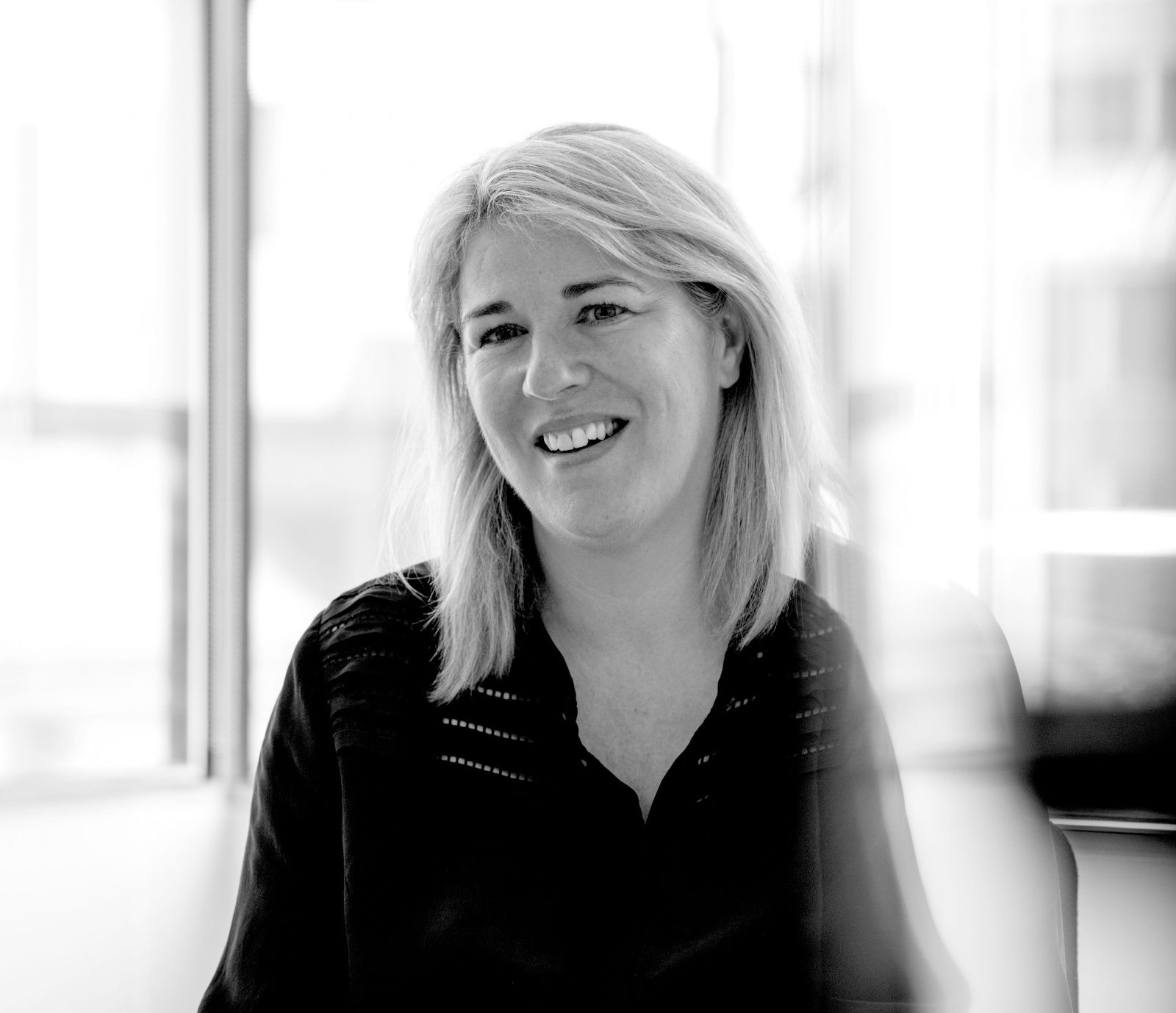 Black-and-white portrait of Recordsure founder Joanne Smith smiling, with shoulder-length fair hair